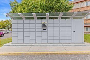 A grey utility box with a black door and a small window is on a sidewalk.